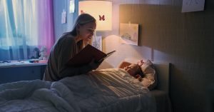 Young Loving Mother Reads Bedtime Stories to Her Little Beautiful Daughter who Goes to Sleep in Her Bed; blog: Healthy Sleep Habits for Kids