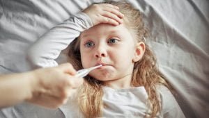 caring mother measures the temperature of a sick little girl; blog: How to Keep Your Child Healthy This Flu Season