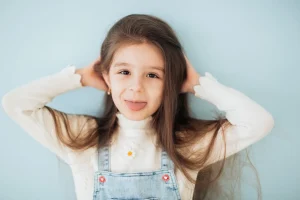 Cute child playfully sticking out tongue against a blue background.