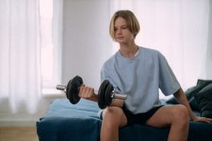 young teen lifting weights in his room